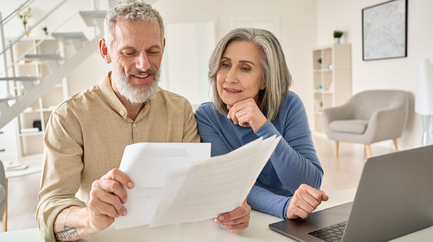 Mains feuilletant des documents administratifs sur une table de cuisine avec une tasse de café